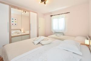 a white bedroom with two beds and a mirror at Apartment Neyra in Split