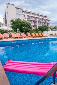 une piscine avec des chaises et un hôtel en arrière-plan dans l'établissement Hotel Central, à Sunny Beach