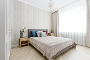 a white bedroom with a bed and a large window at Ausekla Deluxe Apartment in Riga