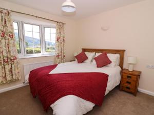 a bedroom with a large bed with red and white sheets at Pen Y Maes in Builth Wells