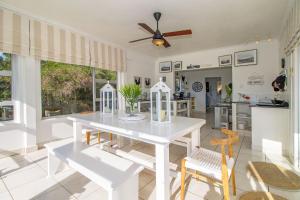 a white dining room with a white table and chairs at The Sullies in Morganʼs Bay