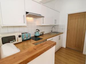 a kitchen with white cabinets and a microwave on a counter at The Button Box in Huddersfield