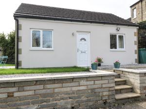 a white house with a brick retaining wall at The Button Box in Huddersfield