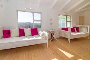 a living room with two benches and windows at The Sullies in Morganʼs Bay