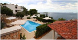 a view of a swimming pool with umbrellas and the ocean at Apartments Tomas in Primošten