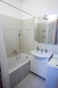 ein Badezimmer mit einem Waschbecken, einer Badewanne und einem Spiegel in der Unterkunft Prémium Home in Pécs