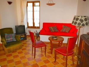Gite Le Lavoir - La Poterie في Caunes-Minervois: غرفة معيشة مع أريكة حمراء وكراسي