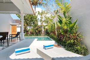- une piscine avec 2 chaises longues à côté d'une maison dans l'établissement Villa Luma, à Seminyak