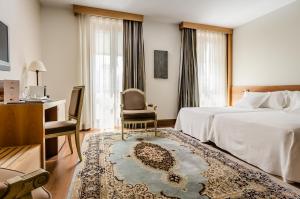 a hotel room with a bed and a chair and a desk at Gran Hotel La Perla in Pamplona
