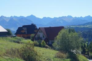 una casa en una colina con montañas en el fondo en Apartamenty i pokoje rodzinne, en Czarna Góra