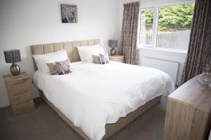 a bedroom with a large white bed and a window at 8 Glamaig Place in Portree