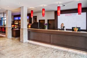 a woman talking on a phone in a hotel lobby at IntercityHotel Berlin Airport Area North in Schönefeld