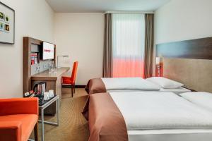 a hotel room with a bed, chair, desk and a television at IntercityHotel Berlin Brandenburg Airport in Schönefeld
