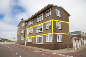 un bâtiment en briques brunes avec des fenêtres blanches sur une rue dans l'établissement kustappartementenkatwijk, à Katwijk aan Zee