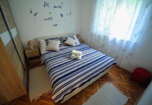 a bedroom with a bed with a blue and white striped blanket at Green Garden Apartment in Split