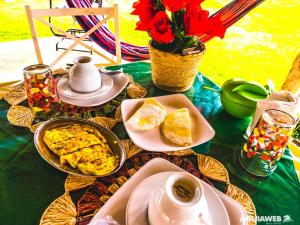 a table with plates of food and cups of coffee at Pousada Da Bell in Barreirinhas +30 photos