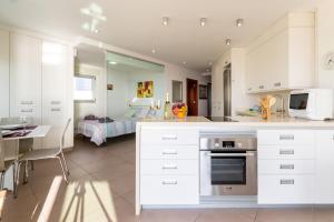 a kitchen with white cabinets and a bedroom at Living Las Canteras Homes - BEACHFRONT PLAYA GRANDE in Las Palmas de Gran Canaria