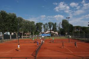 un gruppo di persone che giocano a tennis su un campo da tennis di Residence Diapason a Caorle