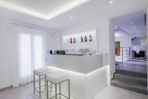 a white kitchen with a counter and stools at Ossuna Bay Hotel Boutique in Cefalù