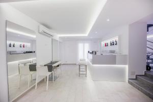 a white room with a table and chairs and stairs at Ossuna Bay Hotel Boutique in Cefalù