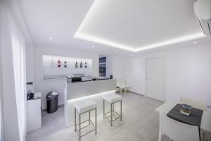 a white kitchen with a counter and stools at Ossuna Bay Hotel Boutique in Cefalù