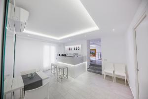 a white kitchen with a counter and chairs in it at Ossuna Bay Hotel Boutique in Cefalù
