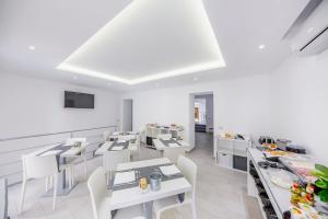 a dining room with white tables and white chairs at Ossuna Bay Hotel Boutique in Cefalù