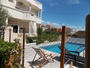 a fence with two chairs and a swimming pool at Rocco apartments in Pag
