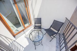 two chairs and a glass table on a balcony at Ossuna Bay Hotel Boutique in Cefalù