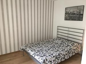Bett in einem Zimmer mit gestreiften Wänden in der Unterkunft Apartament Praga in Warschau