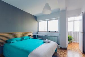 ア・コルーニャにあるTurquoise Apartmentのベッドルーム1室(青いベッド1台、窓2つ付)