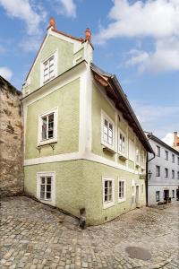 um edifício verde com janelas brancas numa rua em Pension Cortes em Český Krumlov