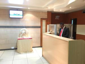 Chester Hotel and Suites Nairobi, City Centre CBD في نيروبي: رجل في بدلة واقف عند كاونتر