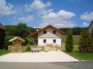 a white house with a wooden fence and a bench at Ferienhaus Geyerbad in Meßstetten