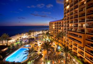 a view of a hotel at night with a swimming pool at Sunset Beach Club Hotel Apartments in Benalmádena
