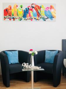 a couch in a living room with colorful birds on the wall at KriDa Comfort Ferienwohnung in Garbsen