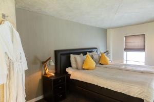 een slaapkamer met een bed met gele kussens en een raam bij Watertorenhotel Nes in Nes