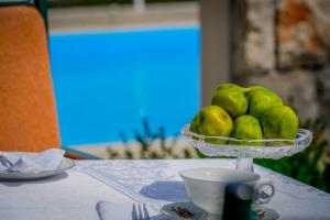 a bowl of green fruit on a table with a cup at Apartments Ivanka in Ston