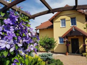 a hedge of purple flowers in front of a house at Jaskółka - pokoje i apartament przy plaży in Olsztyn