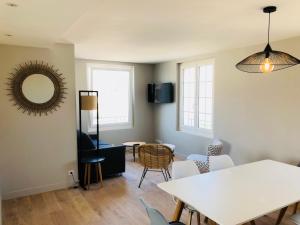 ein Wohnzimmer mit einem weißen Tisch und Stühlen in der Unterkunft Bel Appartement vue mer in Merville-Franceville-Plage