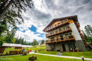 un grand bâtiment avec une cour herbeuse devant lui dans l'établissement Hotel Na Skarpie, à Szklarska Poręba