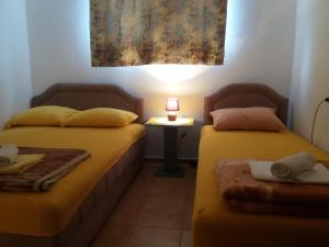 two beds in a room with a lamp on a table at Ori in Podgorica