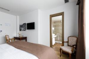 a bedroom with a bed and two chairs and a mirror at Suite Home Pinares in Santander