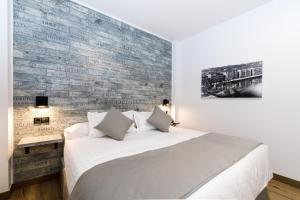 a bedroom with a white bed and a brick wall at Suite Home Pinares in Santander