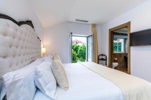 a white bedroom with a large white bed and a window at Suite Home Pinares in Santander
