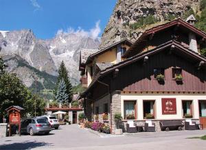 a building with cars parked in front of a mountain at Hotel Dei Camosci in Courmayeur