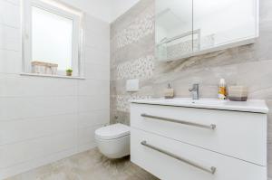 a white bathroom with a toilet and a sink at Beach & park Apartment in Kaštela +21 photos