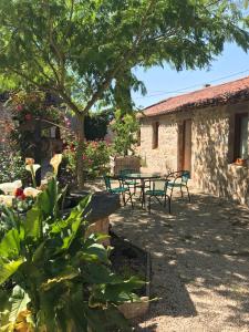 un patio con mesa y sillas bajo un árbol en la raymondiere, en Vernoux-en-Gâtine