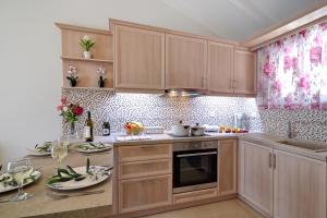 una cocina con armarios de madera y una mesa con platos en Mazis Apartments en Agios Gordios