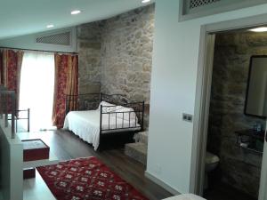 een slaapkamer met een bed en een stenen muur bij A casa de Mateu in Pontevedra